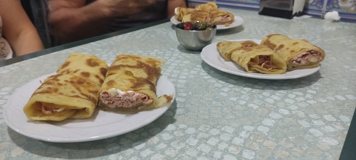 Plato de crepas rellenas de jamón y queso con aceitunas